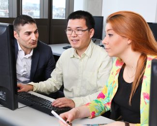 Postgraduate students sitting at a computer